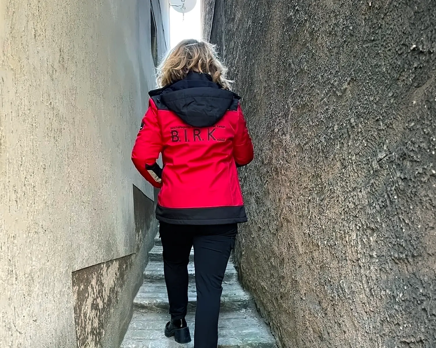 Mitarbeiterin von B.I.R.K. asbl im roten Firmenoutfit bei der Arbeit